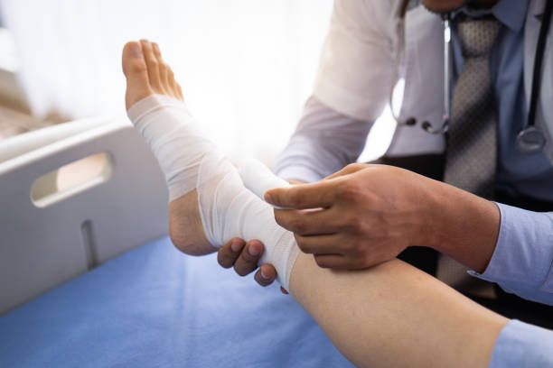 Broken ankle personal injury claim broken leg patient on the bed ,Doctor or physiotherapist giving the expert treatment to the broken leg patient on the bed for a good recovery,Patient with knee problem at consulting room